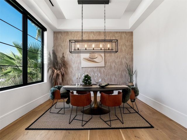 dining room featuring a raised ceiling, an inviting chandelier, and hardwood / wood-style flooring