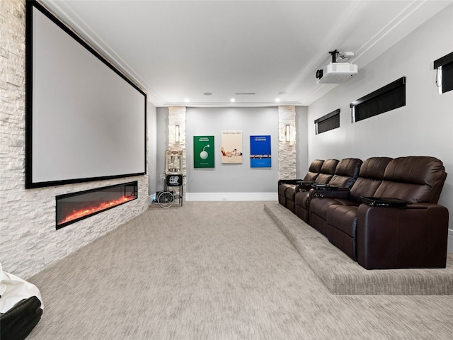 carpeted cinema with a stone fireplace and crown molding