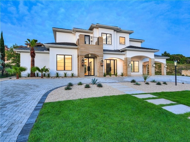 view of front of property with a balcony, a front yard, and french doors