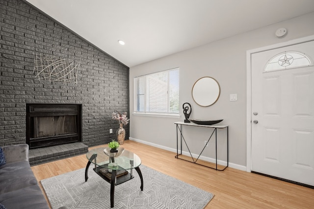 living room featuring brick wall, hardwood / wood-style floors, vaulted ceiling, and a fireplace