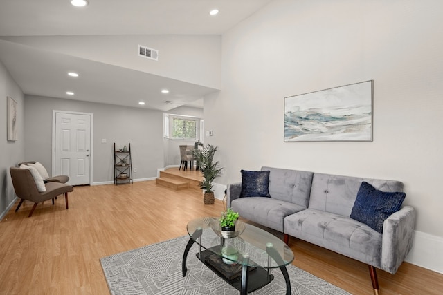 living room featuring high vaulted ceiling and light hardwood / wood-style floors