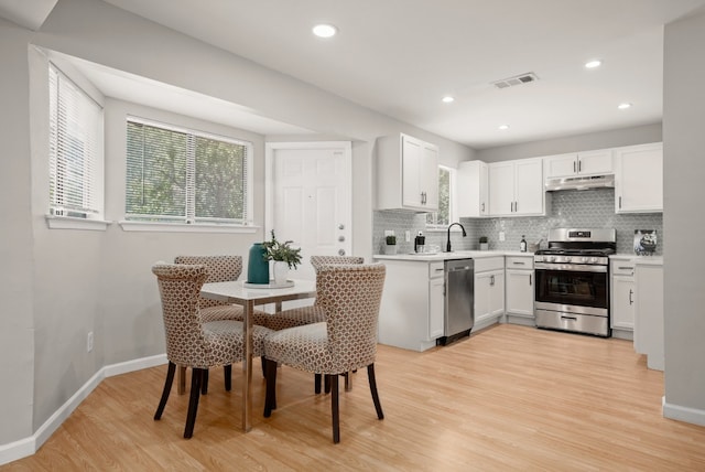 kitchen featuring stainless steel appliances, a wealth of natural light, white cabinetry, and light hardwood / wood-style flooring