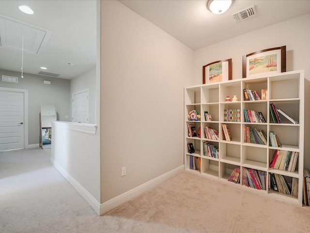 interior space with carpet, visible vents, attic access, an upstairs landing, and baseboards