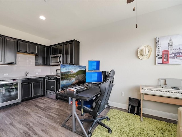 office area featuring recessed lighting, beverage cooler, a sink, wood finished floors, and baseboards