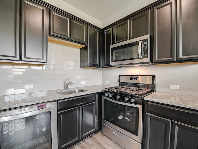 kitchen with light stone counters, wine cooler, stainless steel appliances, tasteful backsplash, and a sink