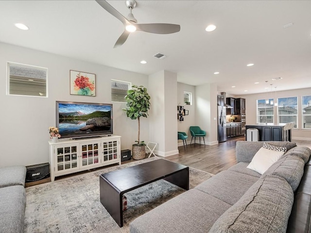 living room featuring a ceiling fan, recessed lighting, visible vents, and wood finished floors