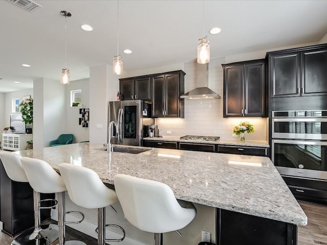 kitchen with a spacious island, visible vents, appliances with stainless steel finishes, decorative backsplash, and wall chimney exhaust hood