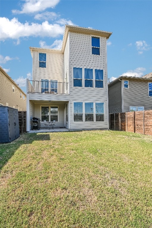 rear view of house with a balcony, a patio area, a fenced backyard, and a lawn