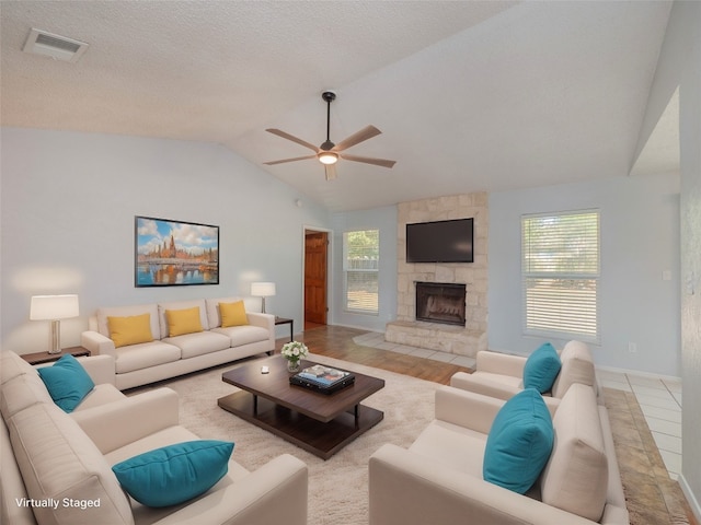 living room featuring a fireplace, a wealth of natural light, ceiling fan, and lofted ceiling