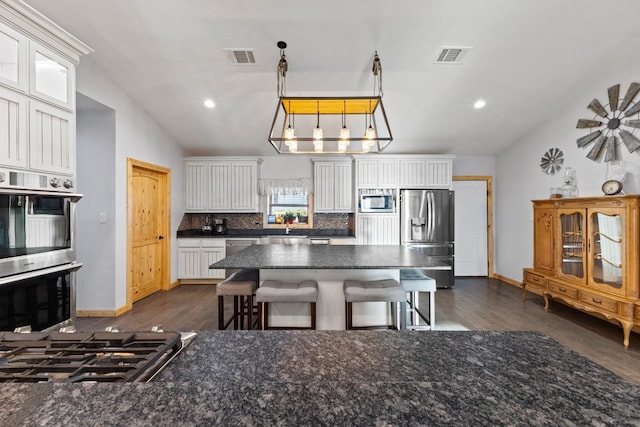 kitchen with white cabinetry, appliances with stainless steel finishes, hanging light fixtures, and vaulted ceiling