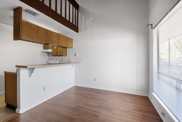 kitchen featuring a textured ceiling, kitchen peninsula, a breakfast bar area, and dark hardwood / wood-style floors