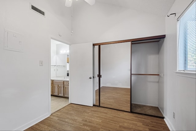 unfurnished bedroom with a closet, light wood-type flooring, lofted ceiling, and ceiling fan