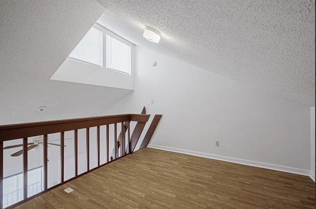 bonus room with hardwood / wood-style flooring, lofted ceiling, a textured ceiling, and ceiling fan