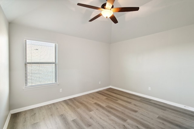 empty room with hardwood / wood-style floors, ceiling fan, and vaulted ceiling