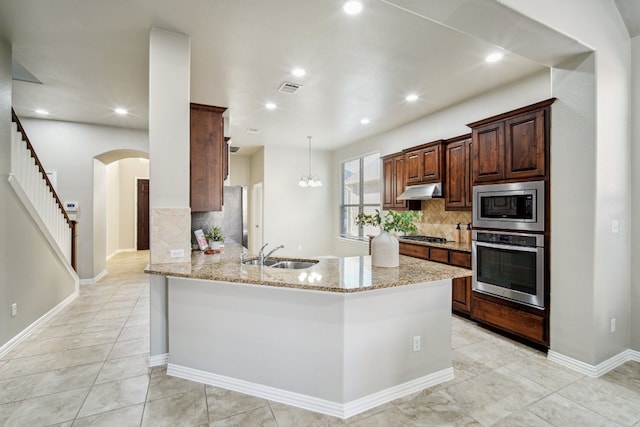 kitchen with light stone counters, backsplash, appliances with stainless steel finishes, sink, and kitchen peninsula