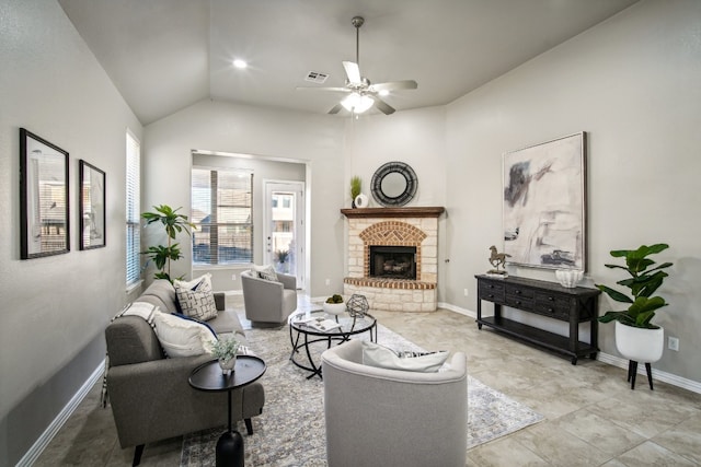 living room with a stone fireplace, lofted ceiling, ceiling fan, and light tile patterned flooring