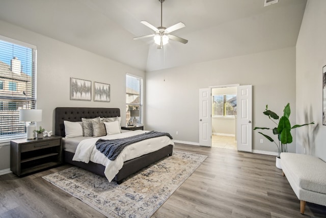 bedroom with ceiling fan, ensuite bathroom, wood-type flooring, and multiple windows