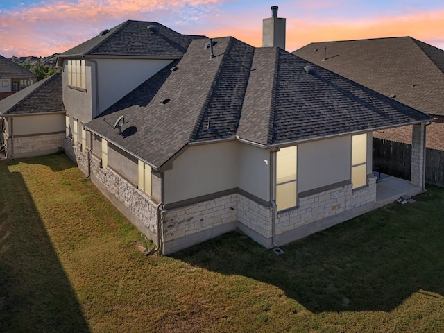 property exterior at dusk featuring a yard