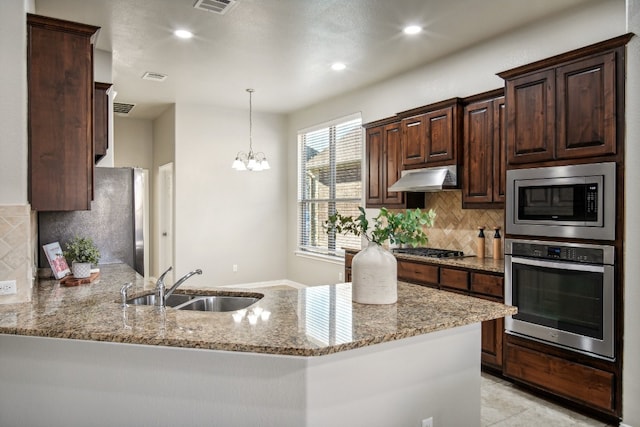 kitchen featuring stainless steel appliances, dark brown cabinetry, sink, light stone counters, and kitchen peninsula