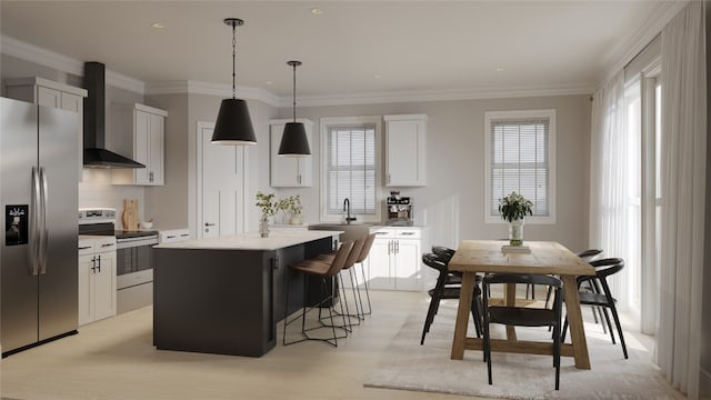 kitchen featuring a kitchen island, wall chimney range hood, appliances with stainless steel finishes, pendant lighting, and white cabinets