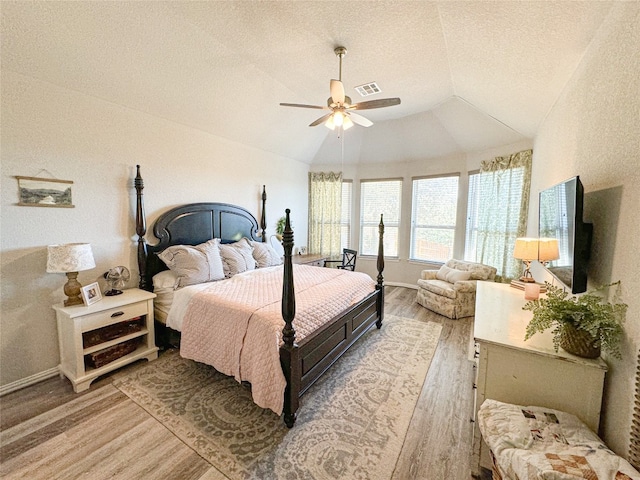 bedroom featuring light hardwood / wood-style floors, ceiling fan, a textured ceiling, and lofted ceiling