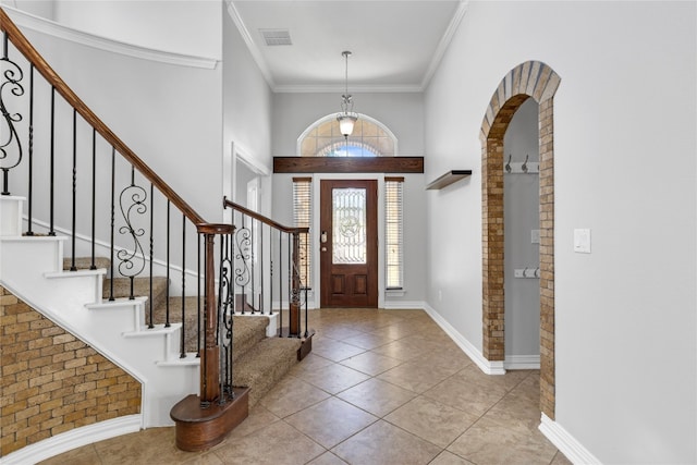 tiled foyer entrance featuring a high ceiling and crown molding