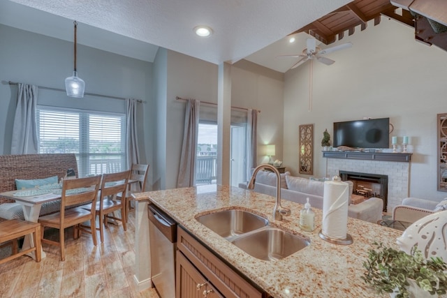 kitchen with a fireplace, high vaulted ceiling, pendant lighting, sink, and dishwasher