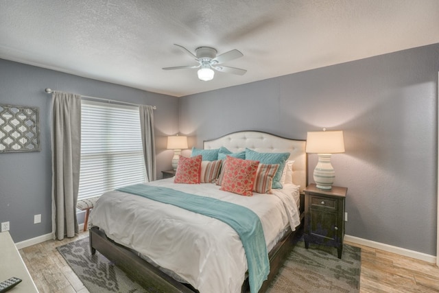 bedroom featuring light hardwood / wood-style floors, ceiling fan, and a textured ceiling