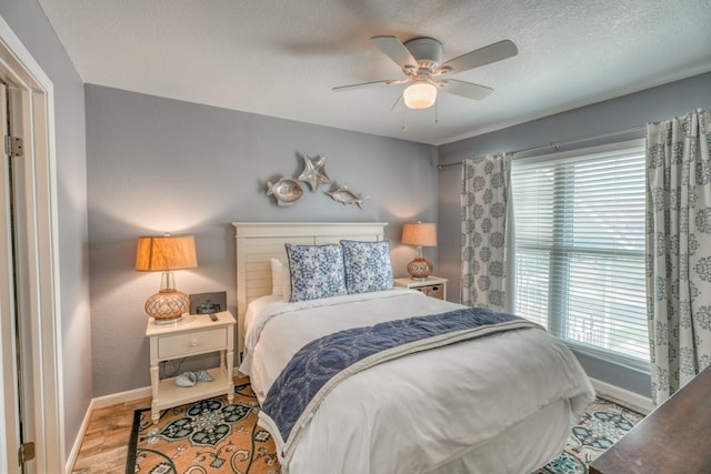 bedroom featuring hardwood / wood-style flooring, ceiling fan, multiple windows, and a textured ceiling