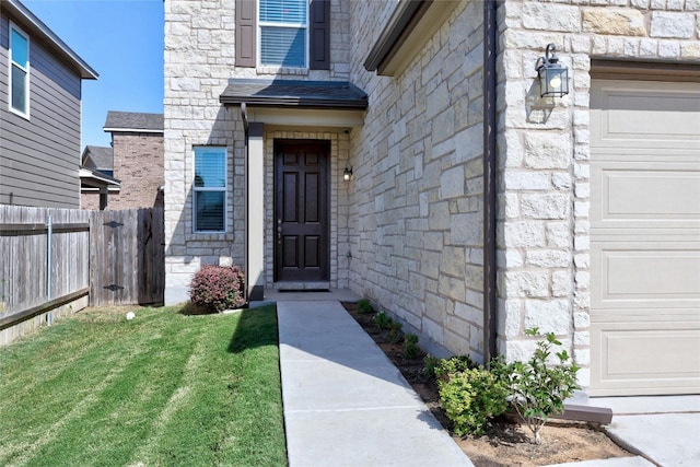 entrance to property featuring a garage and a lawn