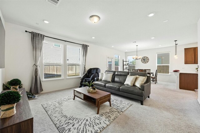 living room with an inviting chandelier, light carpet, and a healthy amount of sunlight