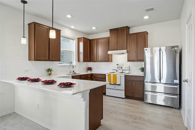 kitchen with pendant lighting, kitchen peninsula, stainless steel refrigerator, and electric range oven