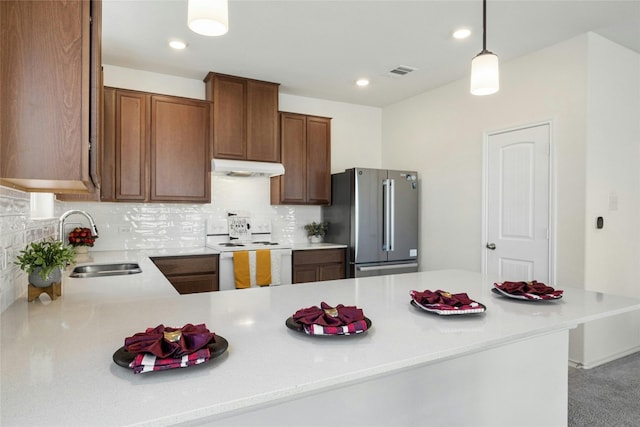 kitchen with stainless steel fridge, backsplash, hanging light fixtures, sink, and white electric range