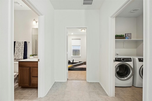 laundry area with washing machine and clothes dryer and light tile patterned floors