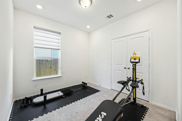 workout room featuring light carpet