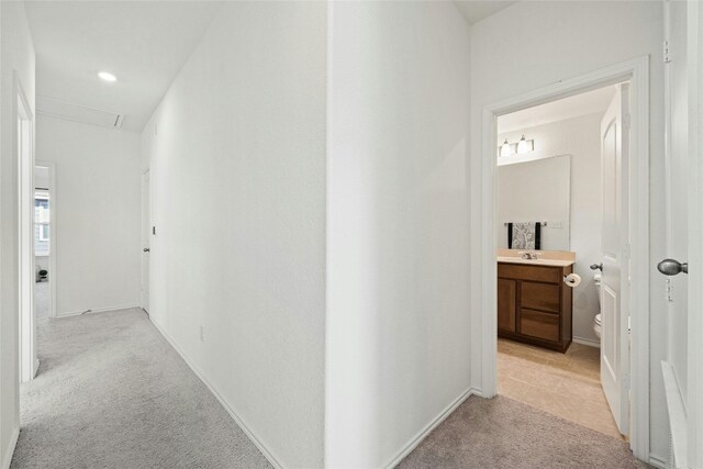 hall with light colored carpet and sink