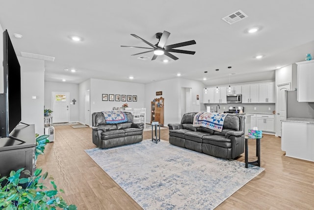 living room featuring light hardwood / wood-style floors, ceiling fan, and sink