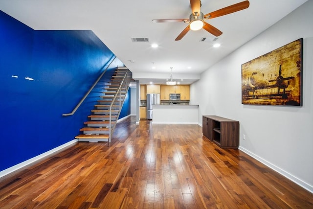 unfurnished living room with ceiling fan with notable chandelier and dark wood-type flooring