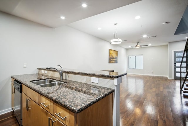 503 Swanee Dr Unit 19, Austin, TX 78752 - kitchen with stainless steel dishwasher, a ceiling fan, brown cabinetry, dark wood-style floors, and dark stone countertops