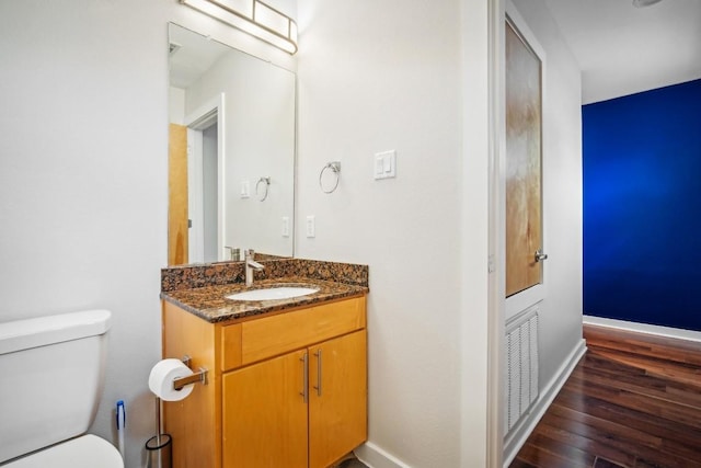 bathroom featuring wood-type flooring, vanity, and toilet