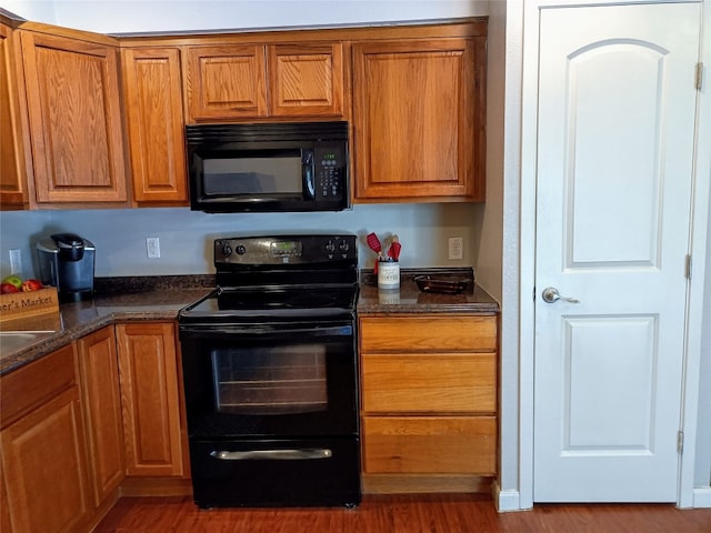 kitchen featuring black appliances, dark stone counters, and dark hardwood / wood-style floors