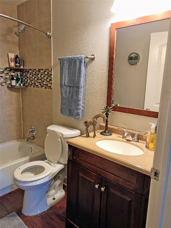 full bathroom with hardwood / wood-style floors, vanity, toilet, and tiled shower / bath