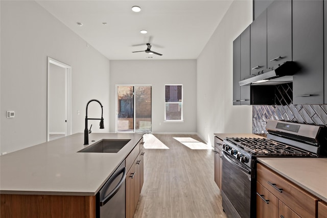 kitchen with sink, light hardwood / wood-style flooring, ceiling fan, stainless steel appliances, and a kitchen island with sink