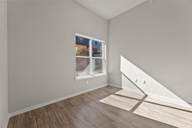 unfurnished room featuring lofted ceiling and hardwood / wood-style flooring