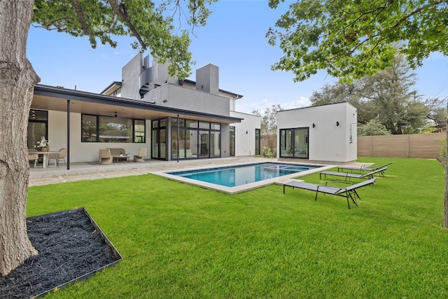 rear view of property with a sunroom, a fenced in pool, ceiling fan, a yard, and a patio