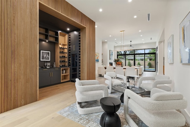 living room with indoor bar, light hardwood / wood-style floors, and ceiling fan