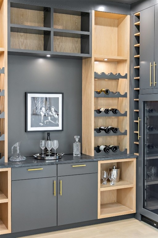 bar featuring gray cabinets, light wood-type flooring, and wine cooler