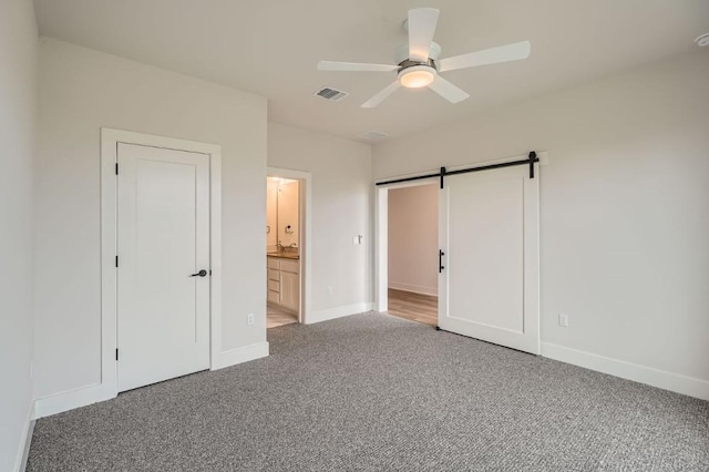 9103 Cattle Baron Path, Austin, TX 78747 - unfurnished bedroom featuring light carpet, baseboards, a barn door, ensuite bathroom, and a ceiling fan