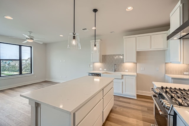 kitchen with a kitchen island, decorative light fixtures, sink, light hardwood / wood-style floors, and white cabinets