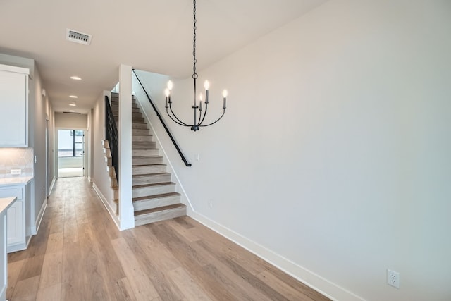 stairs with a chandelier and hardwood / wood-style flooring